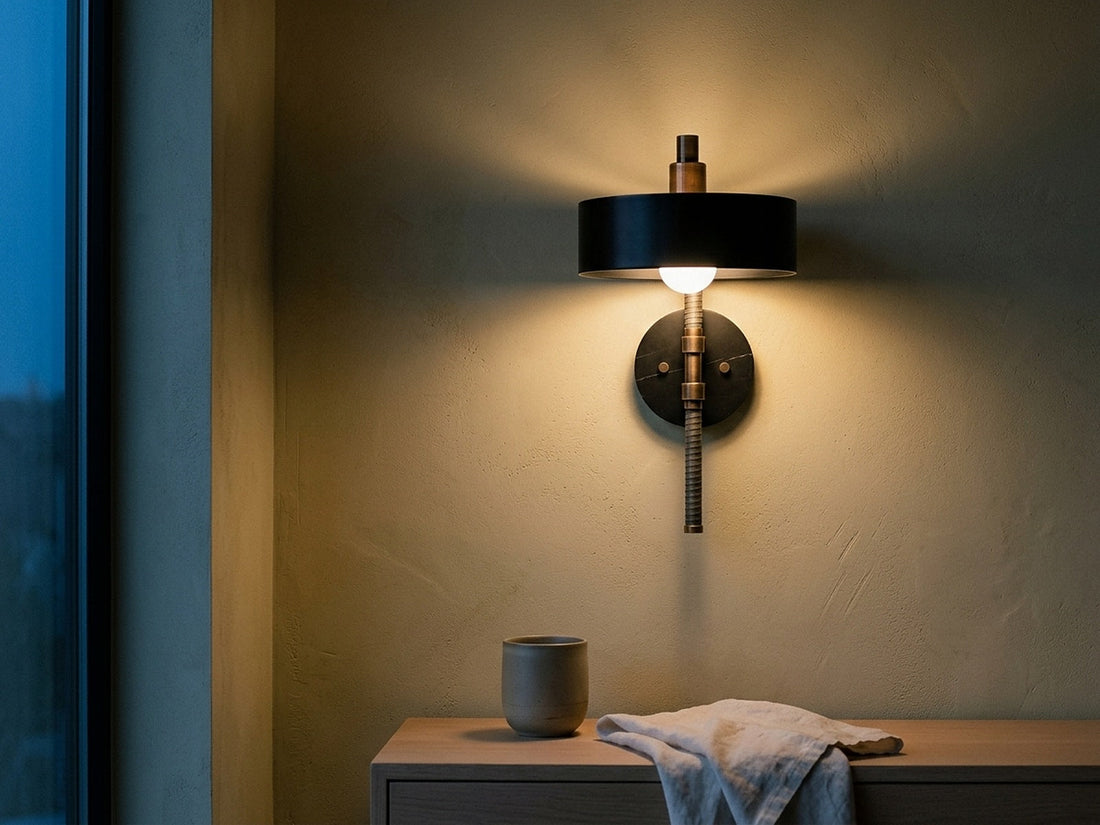 Warm 2700K sconce light on plaster against cool blue evening daylight