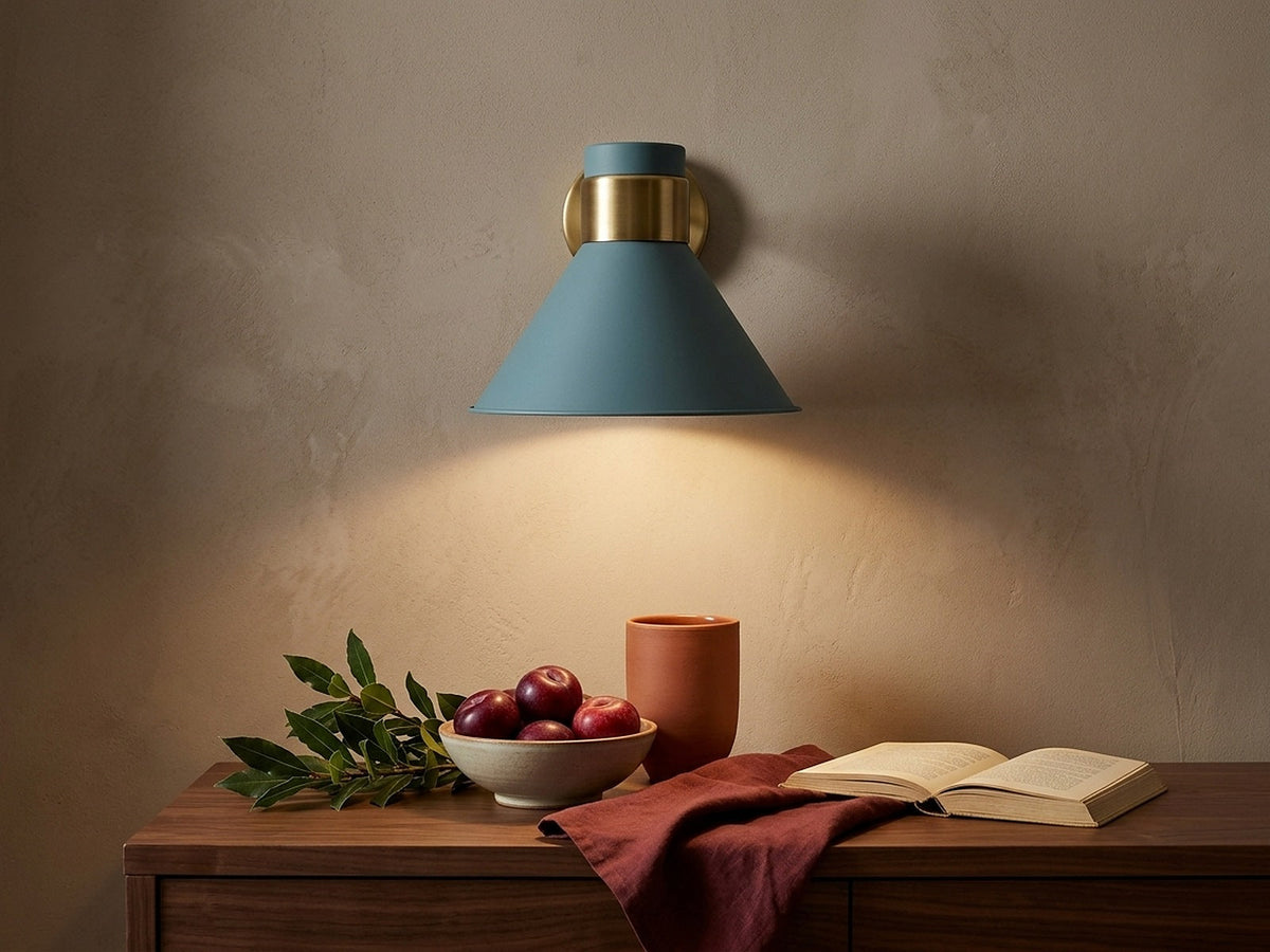 Wall sconce lighting a still life of red plums, terracotta and foliage