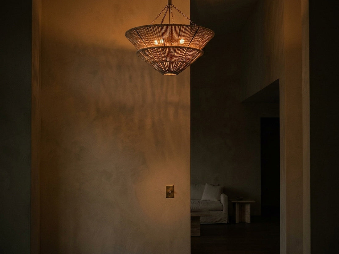 Chandelier dimmed to a low amber glow beside a wall dimmer plate