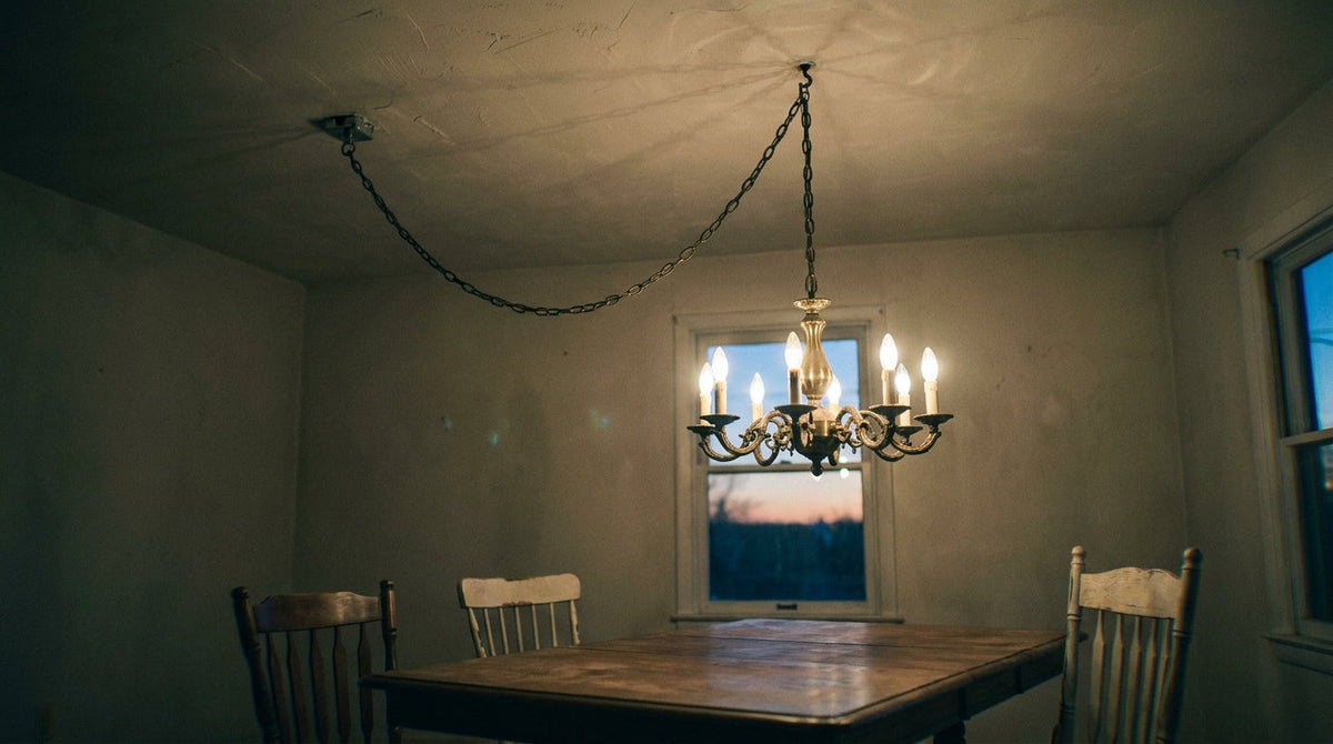 A swagged chandelier hanging centred over a table, its chain running diagonally to an off-centre ceiling box