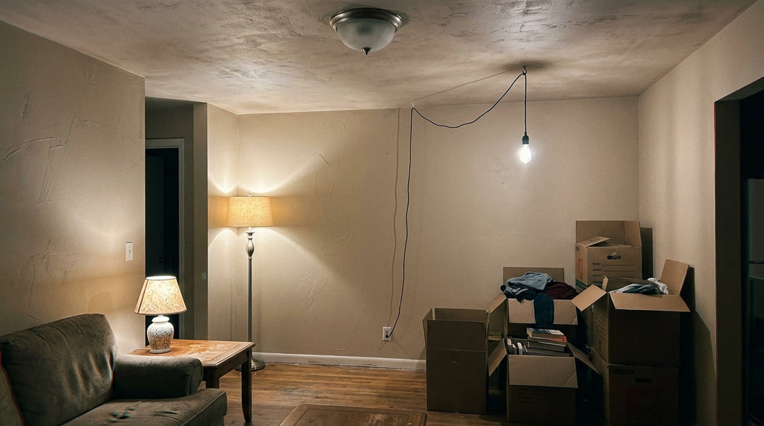 A rented living room lit by plug-in lamps and a swagged cord pendant, with the original ceiling dome switched off